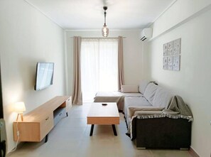 A modern living room with a sofa, a coffee table, a TV, and a wall-mounted artwork.