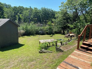 A wooden deck, a shed, and a grassy yard with trees and a fence.
