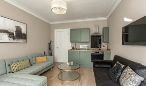 A living room with a sofa, a coffee table, and a TV.