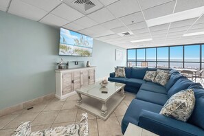 Ein modernes Wohnzimmer mit großem Fenster, einem blauen Sofa, einem weißen Couchtisch und einer Kommode mit Dekoration.