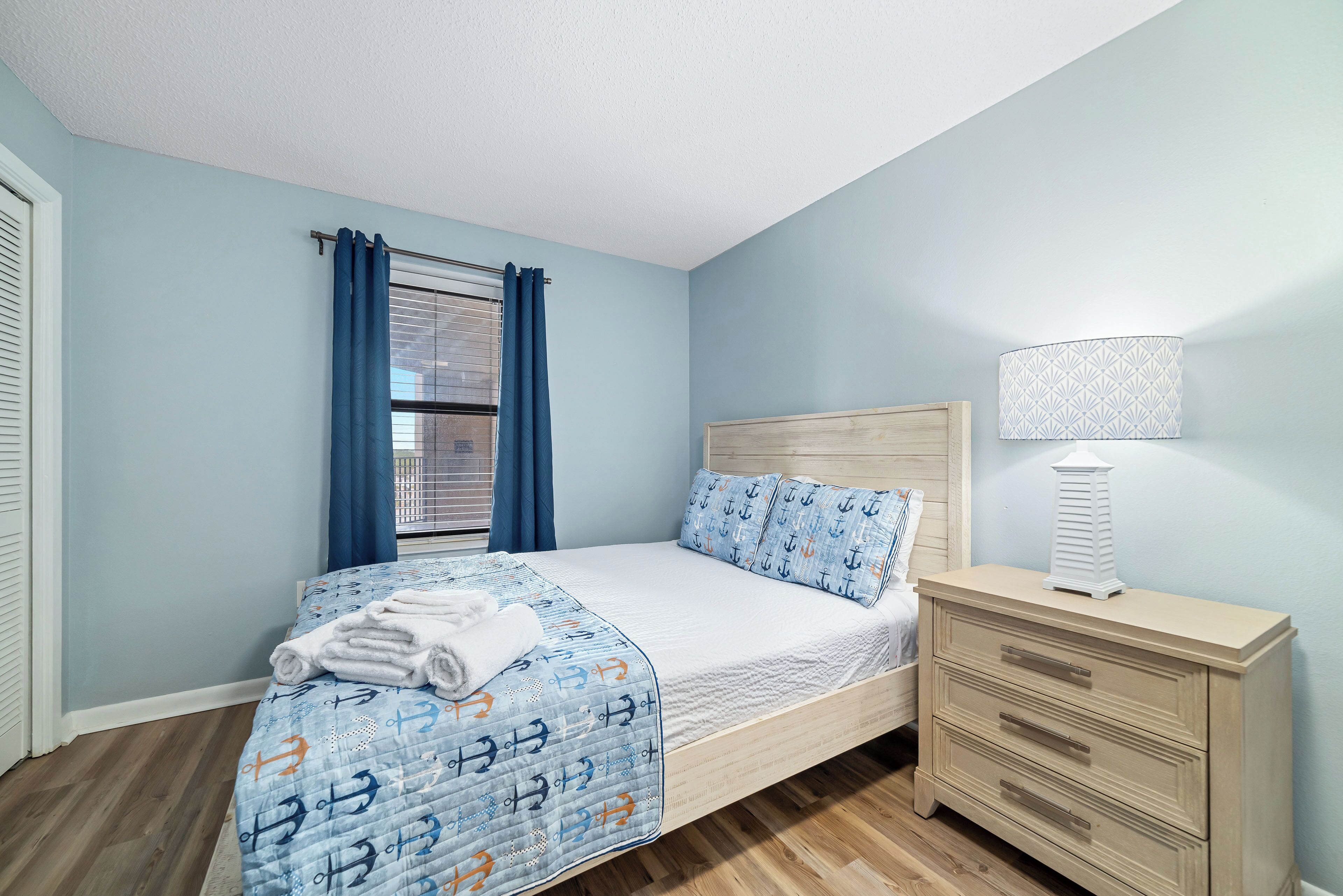 A bedroom with a bed, a nightstand, a lamp, and a window with curtains.
