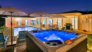 Ein Whirlpool, ein Außenpool, Sonnenschirme und Terrassenmöbel.