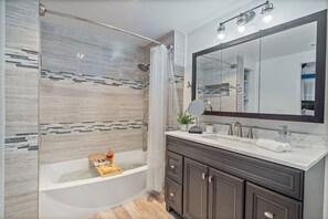 A modern bathroom with a glass-enclosed shower, a large mirror, and dark-toned cabinetry. - Dome Getaway, Hot Tub, Mini Golf, Game Room, Pets (Oakhurst)