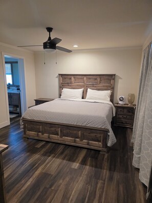 A bedroom with a wooden bed frame, a ceiling fan, and a nightstand with a lamp. - Midlake. Conveniently located close to Toledo Town. Pet friendly. (Many)