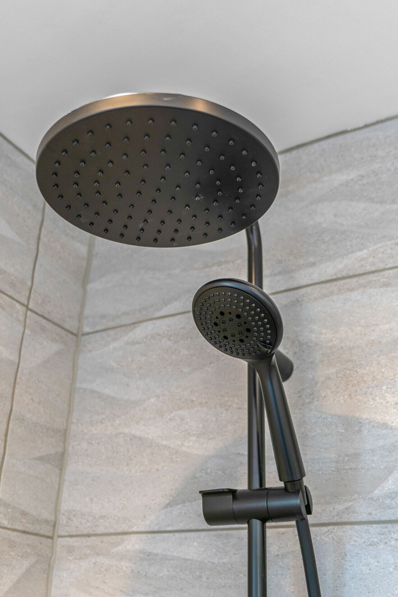 A showerhead with a round, perforated design, mounted on a metal stand.