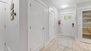 Un pasillo con puertas blancas, un extintor y un tapete estampado.