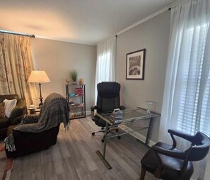 A living room with a sofa, a chair, a glass table, and a lamp.