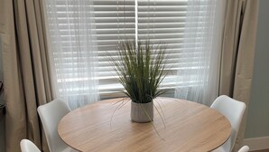 A round wooden table with four white chairs, a potted plant, and sheer white curtains. - Delightful 2 bedroom - Island Cottage (Key Largo)