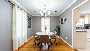 A dining area with a round table, chairs, a chandelier, and a view into the kitchen. - Culmore TX (Houston)