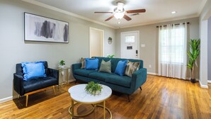 A living room with a dark blue sofa, a teal sofa, a white coffee table, and a ceiling fan. - Culmore TX (Houston)