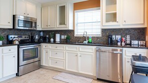A modern kitchen with stainless steel appliances, white cabinetry, and a tiled backsplash. - Culmore TX (Houston)
