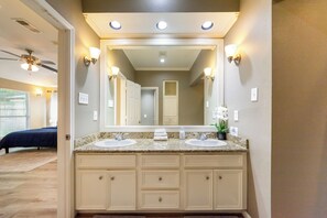 Un baño con dos lavamanos, un espejo grande y apliques de pared.