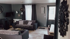 A modern living room with a sofa set, a TV, and a dining area.