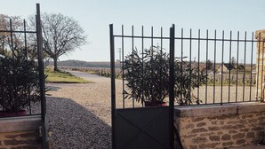 A gated entrance with a gravel path leading to a rural landscape.