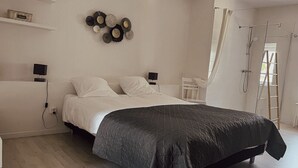 Un dormitorio con una cama, mesitas de noche, un adorno en la pared y un rincón de ducha.