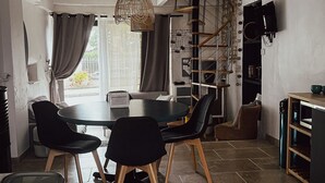 Una cocina moderna con comedor, que presenta una mesa redonda con sillas, una lámpara colgante y un televisor montado en la pared.