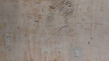 A wall with a faded sketch of a man's face and some writing.