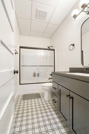 A bathroom with a shower, toilet, and vanity. - American Hall (Millersburg)
