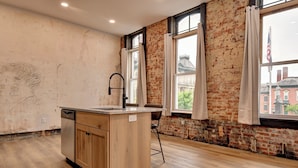 Una cocina con una isla de madera, lavavajillas y una ventana con cortinas.