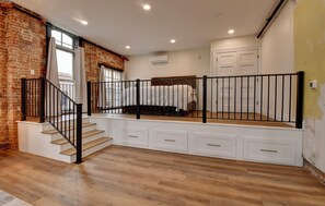 A bedroom with a bed, a staircase with black railings, and a white wall with a window. - American Hall (Millersburg)