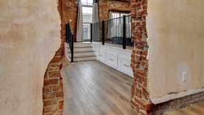 Un interior espacioso con paredes de ladrillo visto, una escalera de madera y vistas al piso superior.