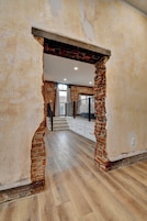 Un interior espacioso con paredes de ladrillo visto, una escalera de madera y vistas al piso superior.