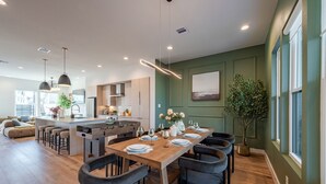 Una cocina moderna con una isla central, comedor con sillas y un amplio ventanal con vistas.