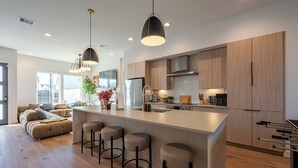 Una cocina moderna con una isla central, taburetes de bar y armarios de madera.