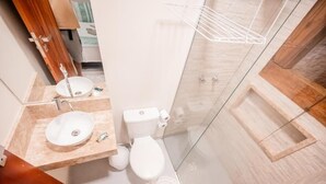 Een moderne badkamer met een houten wastafelmeubel, een witte wastafel, een toilet en een douchecabine van glas.
