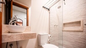 Een moderne badkamer met een wit wastafelmeubel, een toilet en een douchecabine van glas.