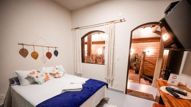 Een slaapkamer met een bed, een houten bureau en een spiegel.