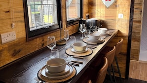 A wooden dining table set with plates, bowls, cutlery, and glasses, with a shield with a cross on the wall behind it. - Copper Castle & Petting Farm near Legoland (Windsor)