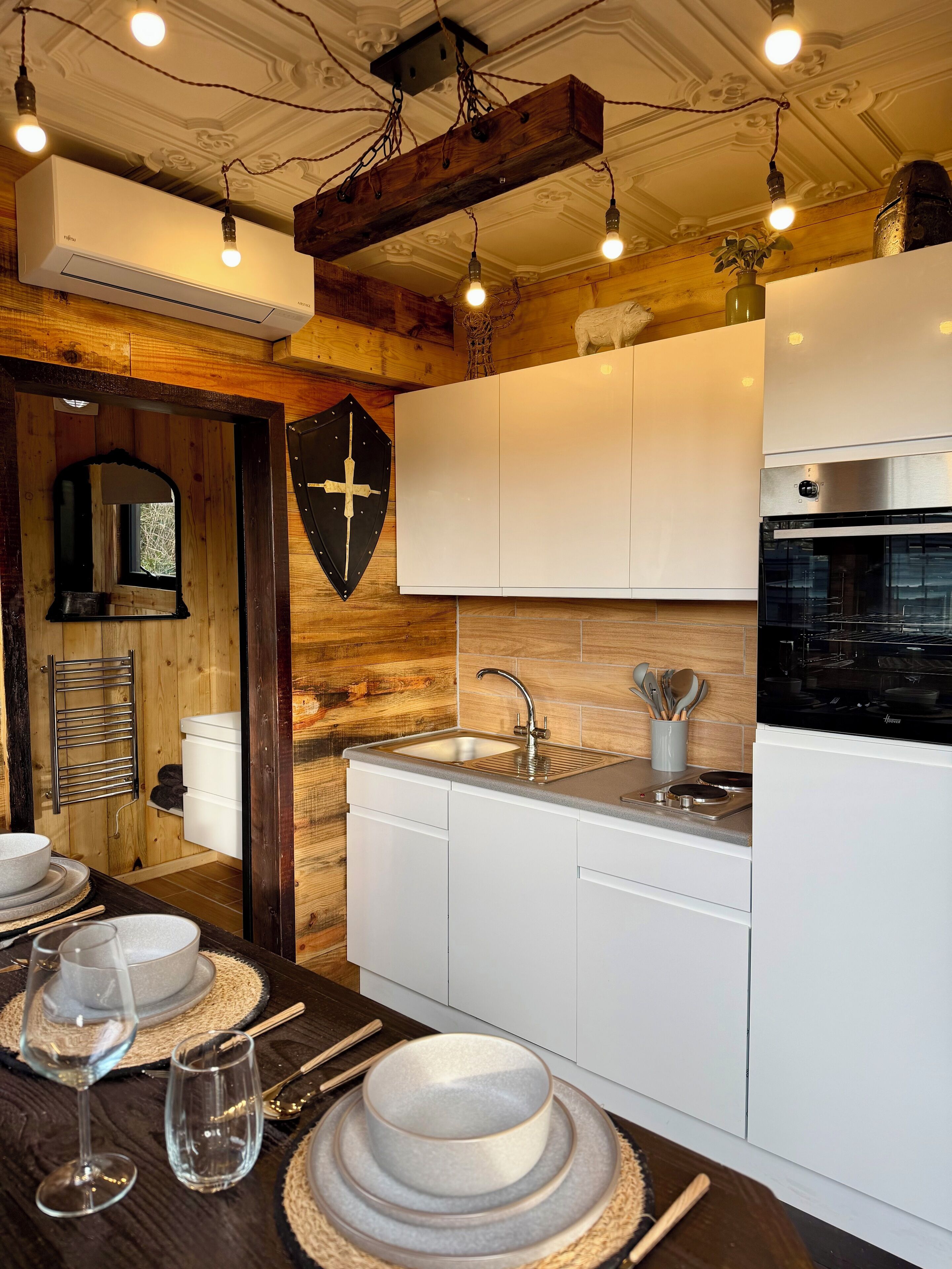 Una cocina moderna con armarios blancos, un lavamanos de acero inoxidable y un horno empotrado.