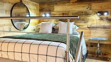 A bunk bed with a metal ladder, a wooden headboard, a mirror, and a small table with a tray.