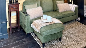 A cozy room with a green sofa, a wooden wall, and a large tapestry. - Copper Castle & Petting Farm near Legoland (Windsor)