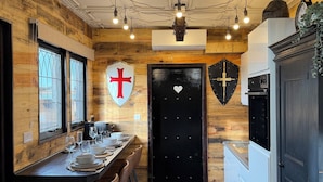 A dining area with a wooden wall, a black door with a heart, and a cross on the wall. - Copper Castle & Petting Farm near Legoland (Windsor)