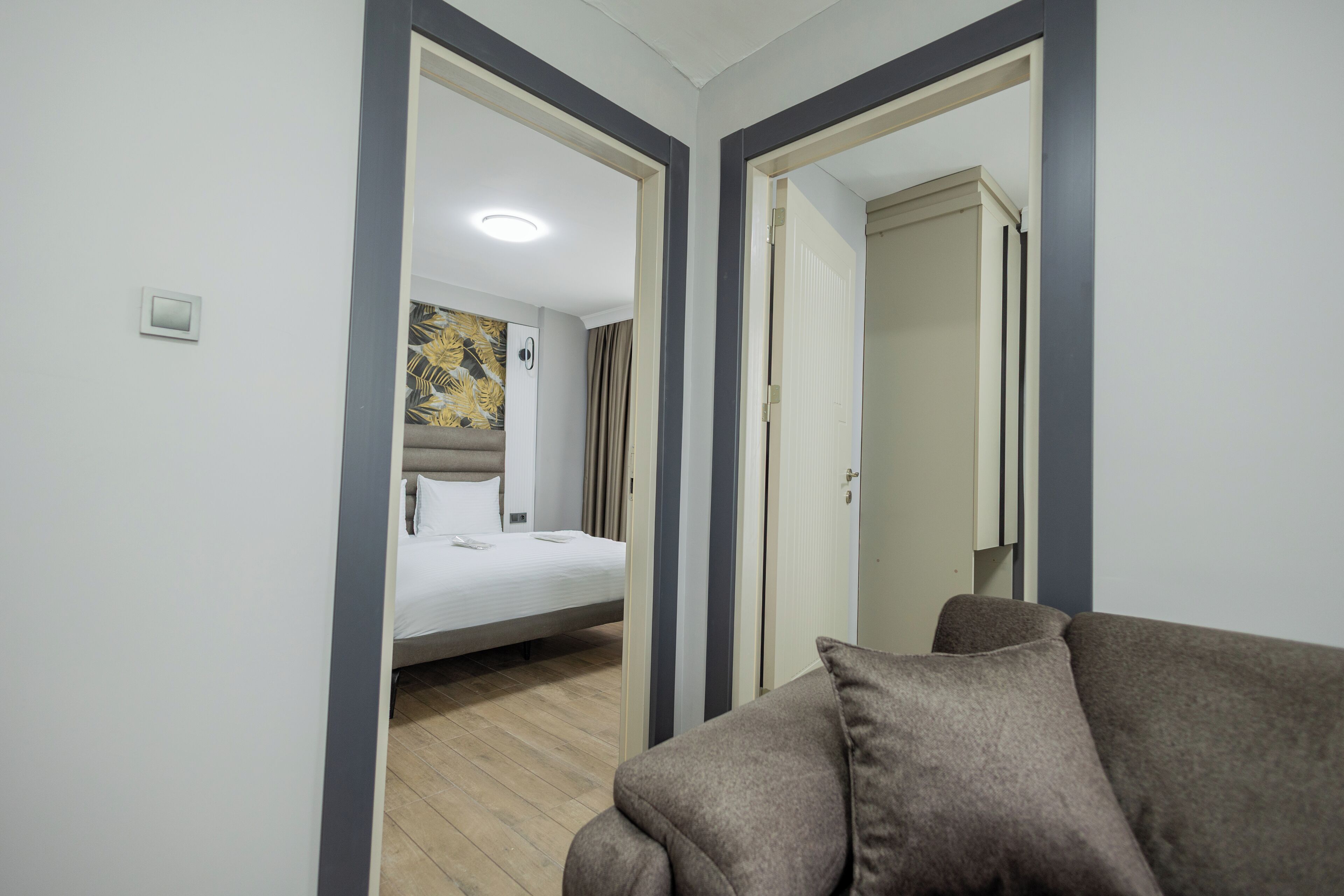 A hotel room with a bed, a sofa, and a mirror reflecting the room.