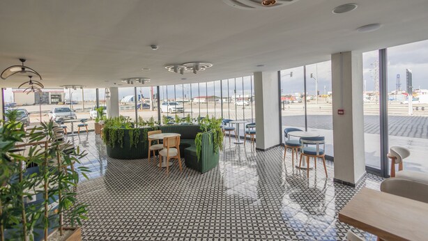 Amplio espacio interior con ventanas grandes, piso estampado y varios conjuntos de asientos.