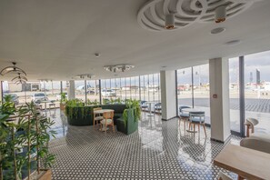 Amplio espacio interior con ventanas grandes, piso estampado y varios conjuntos de asientos.