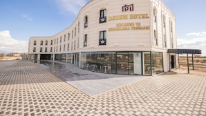 Un hotel moderno con fachada curva, amplios ventanales y una zona de entrada con baldosas.