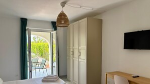 Quarto com cama, escrivaninha, cadeira, guarda-roupa e televisão.