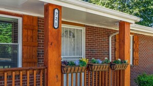 A brick house with a wooden porch, a white door, and a mailbox with the number 721. - Butterfly Bungalow is a 4BR/2BA home with outdoor terrace and grill (Columbus)