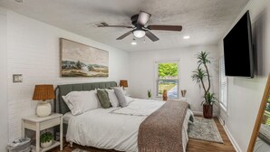 A bedroom with a bed, nightstand, lamp, and a ceiling fan. - Butterfly Bungalow is a 4BR/2BA home with outdoor terrace and grill (Columbus)