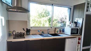 A compact kitchen with a window, a microwave, and a coffee maker. - Fully-equipped 1 room furnished studio without partitions (Chavagnes-en-Paillers)