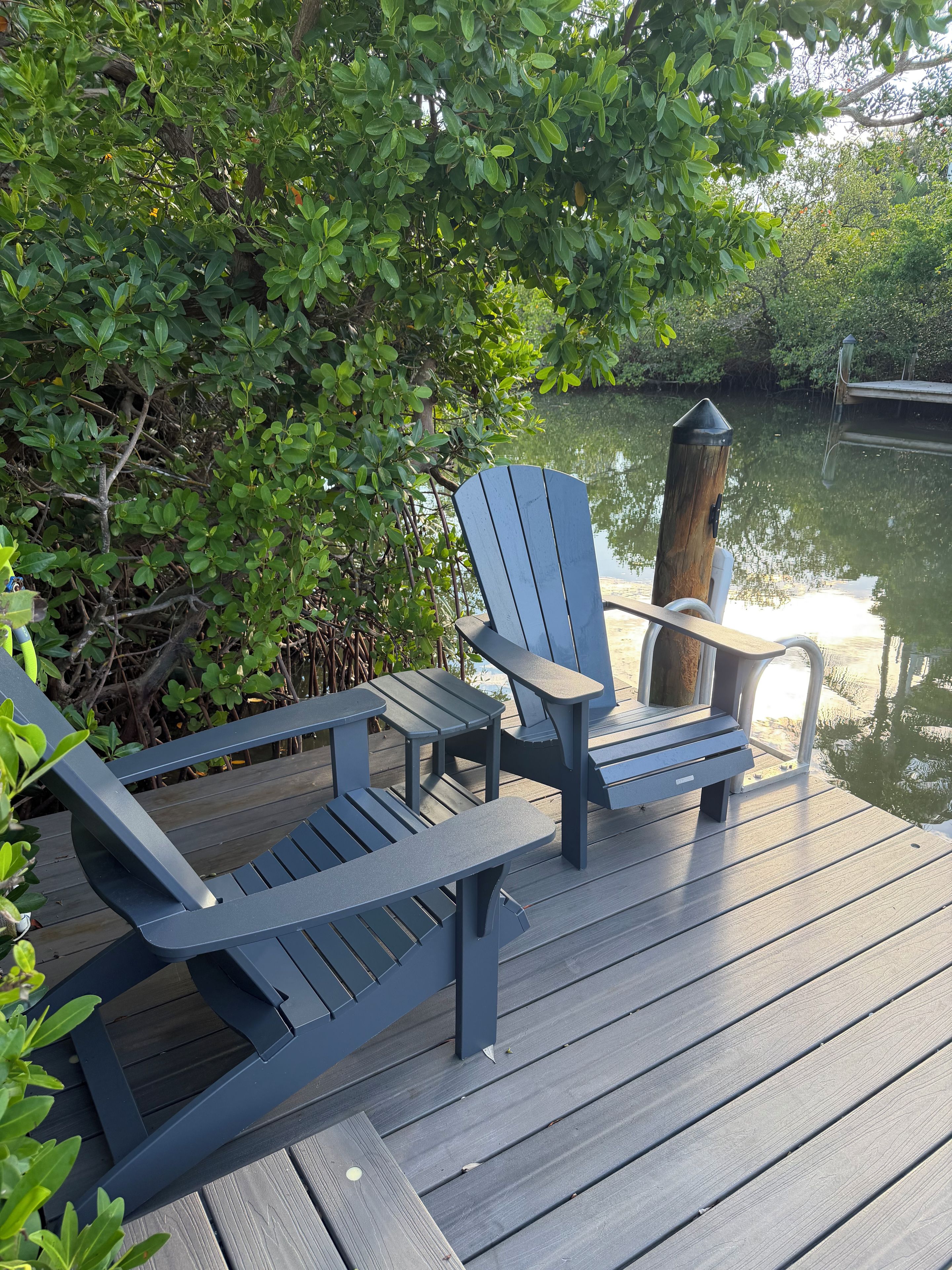 Une terrasse avec des fauteuils Adirondack et un poteau en bois.
