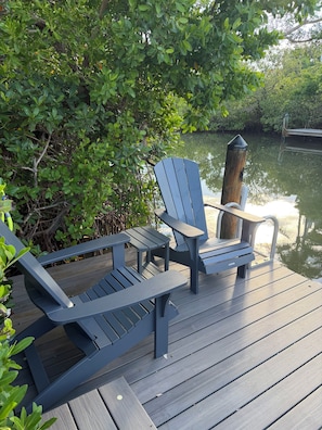 A deck with Adirondack chairs and a wooden post. - Canalfront Siesta key entire King suite  (Sarasota)