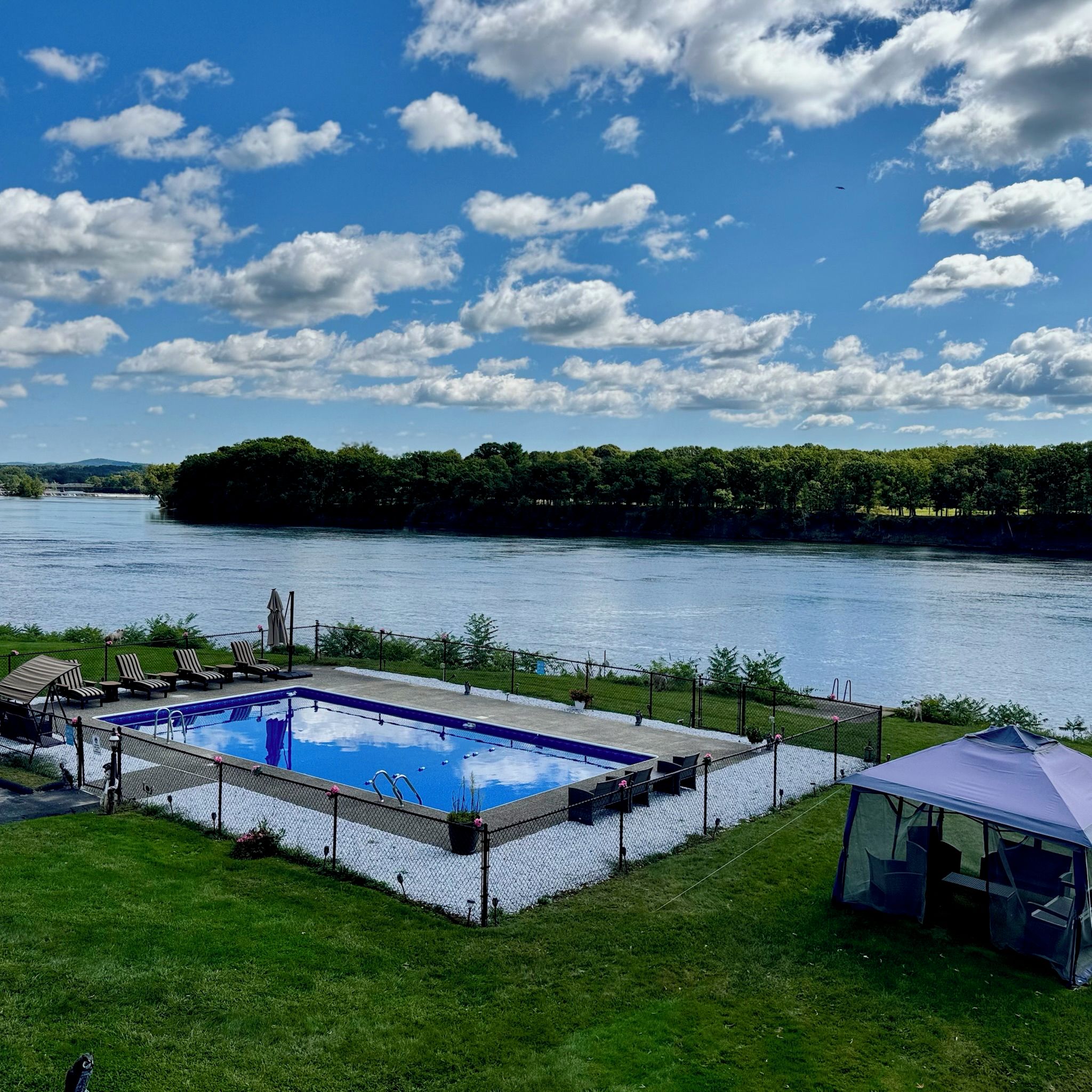 A swimming pool with a view of a river and forested area.
