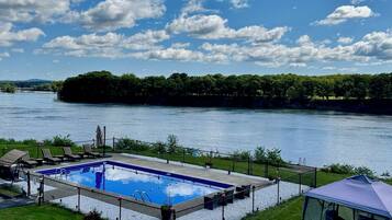 A swimming pool with a view of a river and forested area.