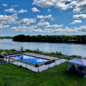 A swimming pool with a view of a river and forested area.
