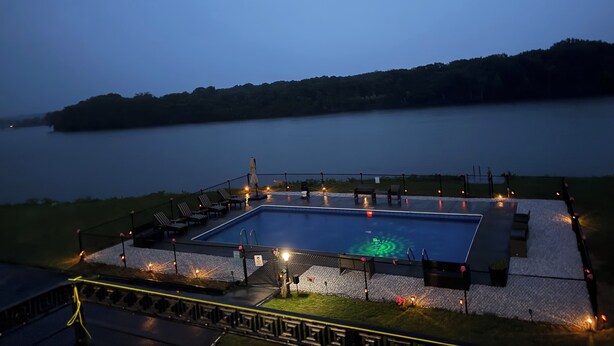 Ein rechteckiger Pool mit umlaufender Liegefläche, einem Zaun und Stühlen.